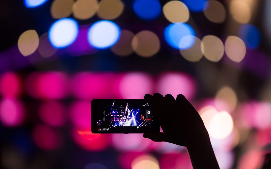 People taking photographs with touch smart phone during a music concert